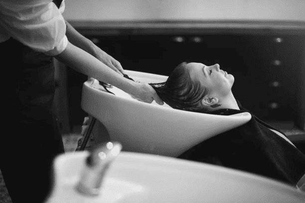 Hair being washed at a salon sink, person relaxing during the process.