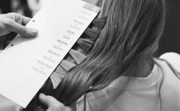 Hair color chart next to woman's hair for matching.