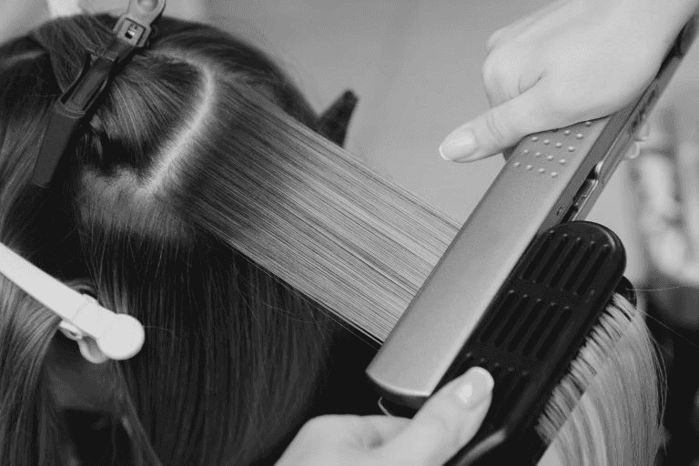 Hair being straightened with a flat iron during a salon treatment.