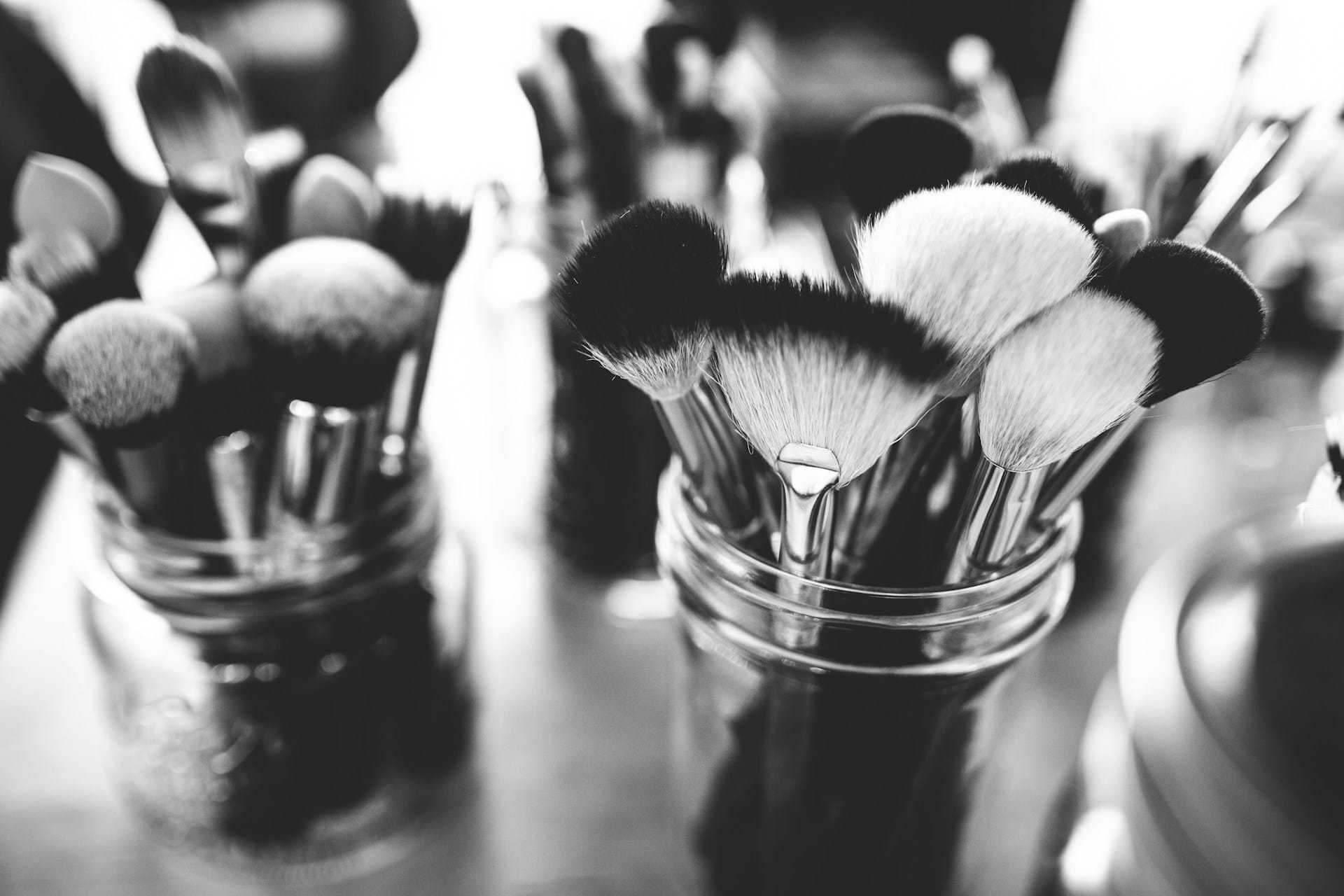 Jars filled with assorted makeup brushes in black and white.
