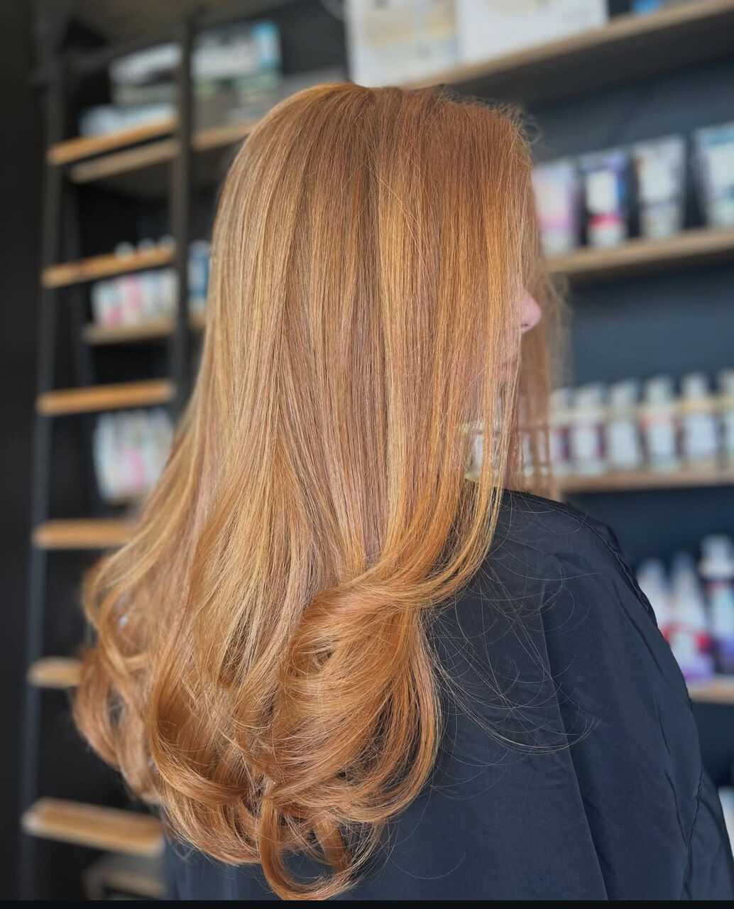Red-haired woman with sleek, voluminous locks in a salon setting.