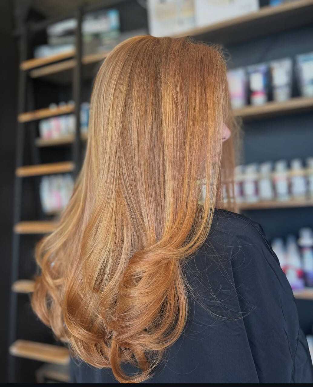 Red-haired woman with sleek, voluminous locks in a salon setting.