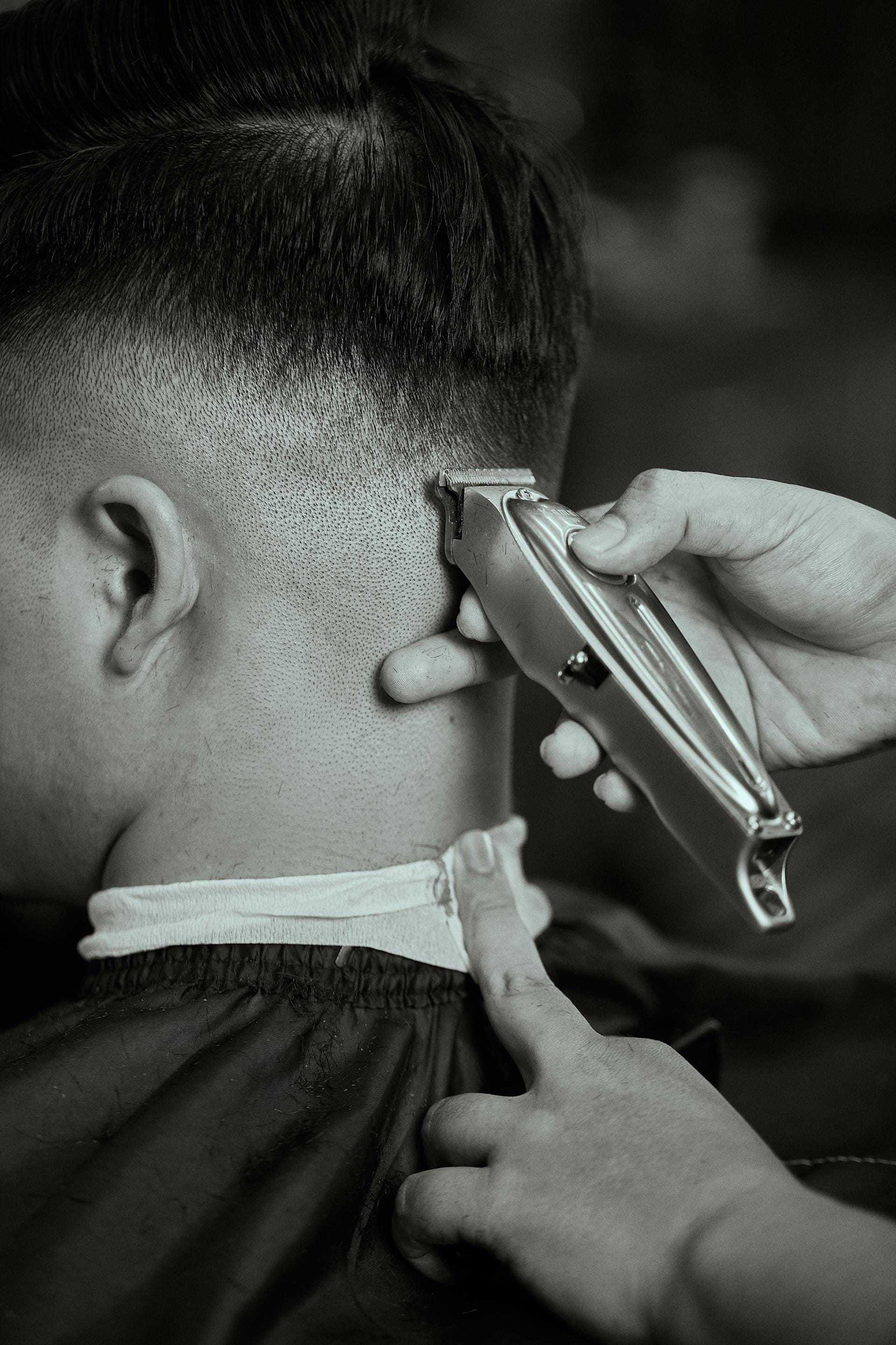 Barber using clippers to trim hair on a man's neck, with focused attention on detail.