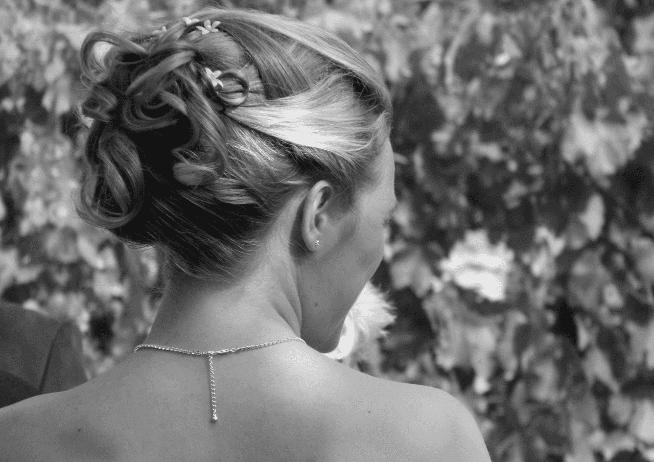 Elegant updo hairstyle with curls and floral hairpin.