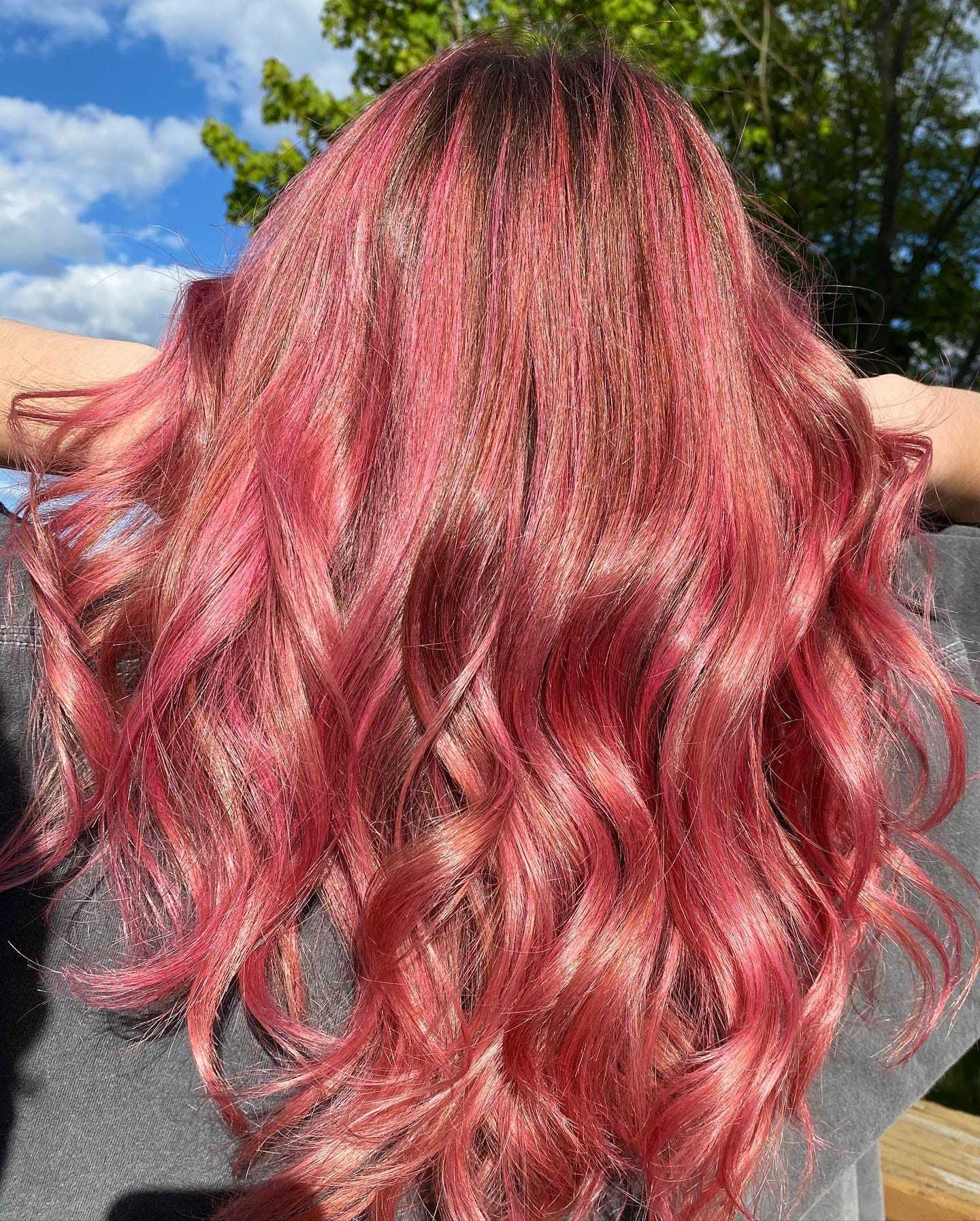 Wavy hair dyed pink with highlights, shown outdoors in sunlight.