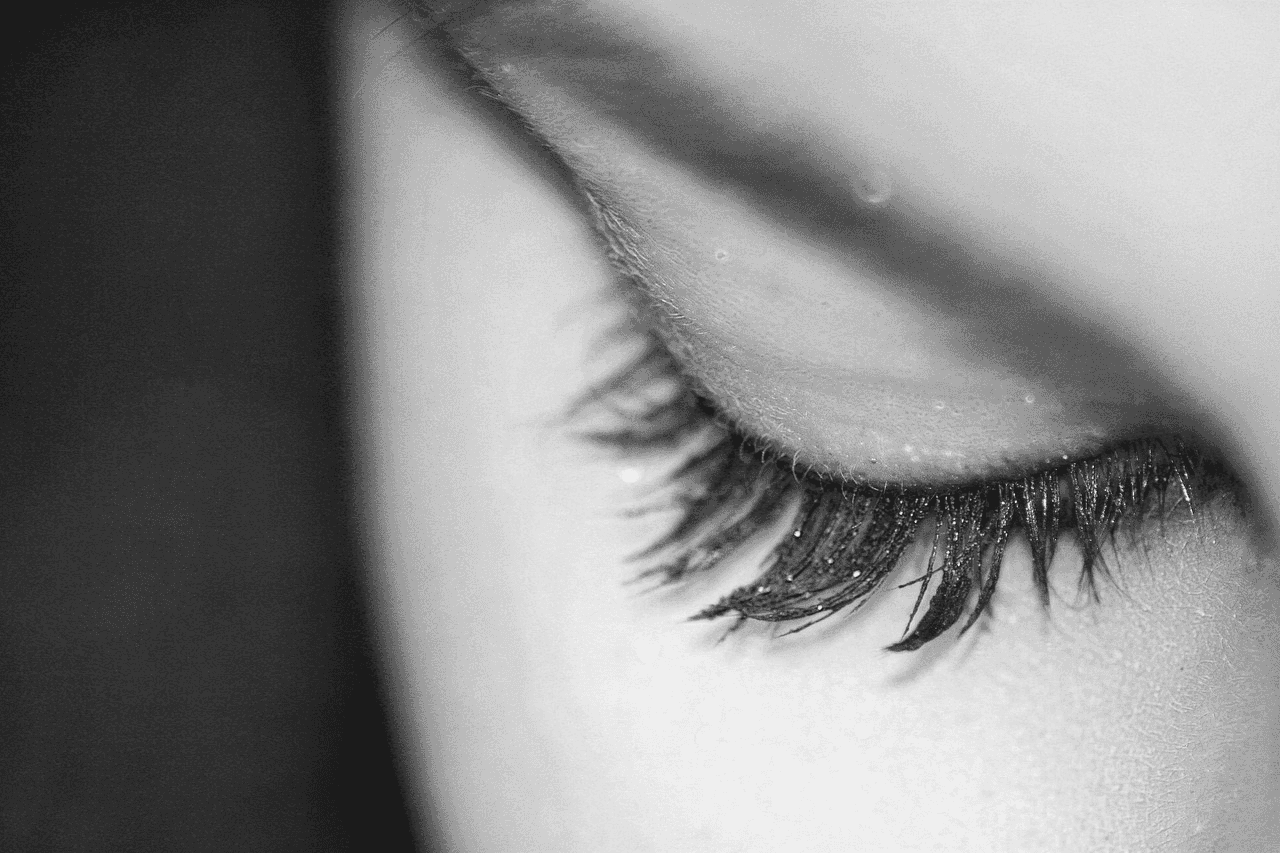 Closed eye with long eyelashes, captured in close-up monochrome detail.